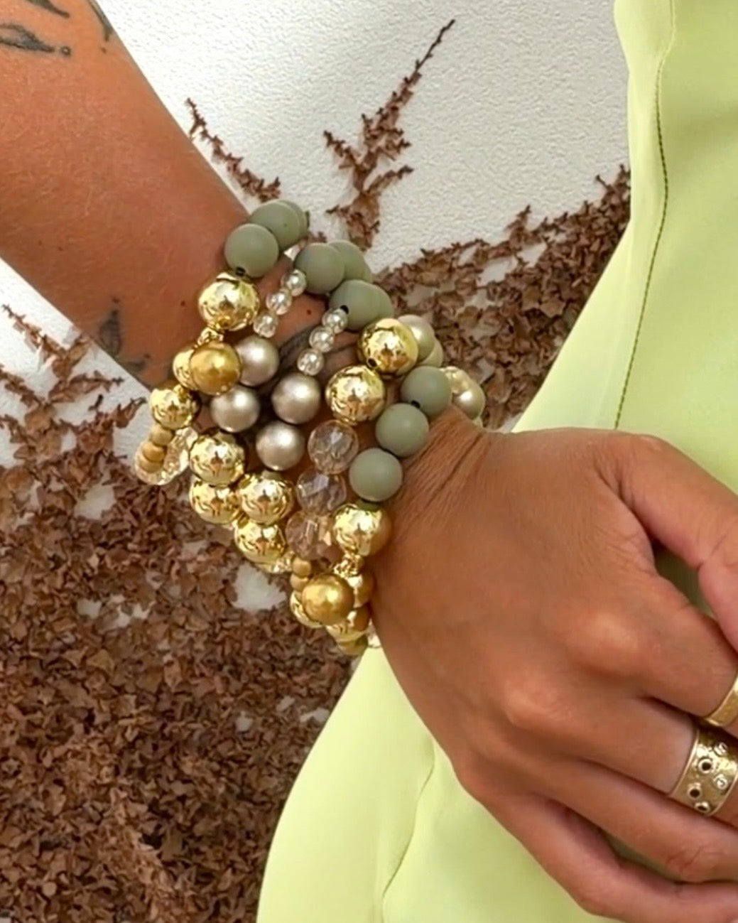 LOVE Beth Mimi Love Luxe Gold Sage Bracelet worn layered with colourful gold bead and crystal bracelets.